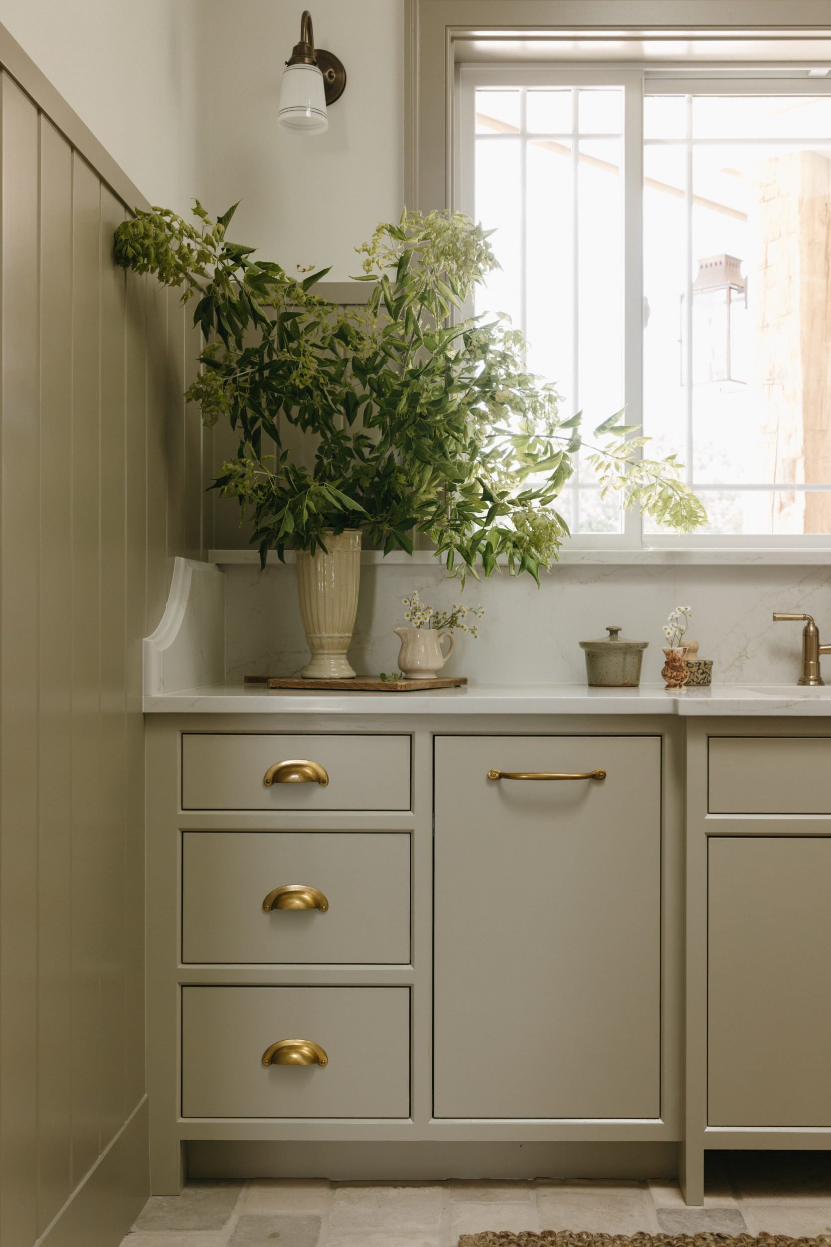 A drawer bank with aged brass bin pulls sits below the window in this Menlo, Iowa laundry room.